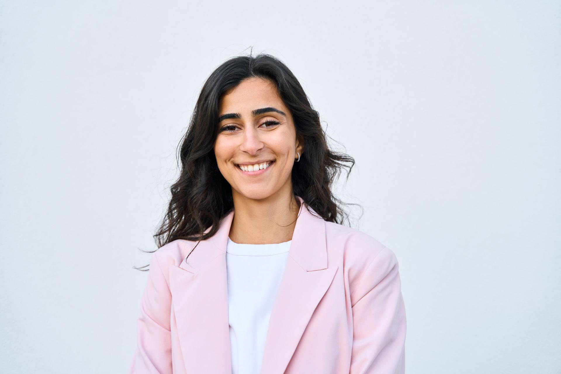 Retrato de primer plano de la mujer de negocios de Israel del Medio Oriente, dama de negocios de pie aislada sobre fondo blanco. Feliz sonriente joven exitosa mujer árabe o india de los años 20 en traje, mirando a la cámara
