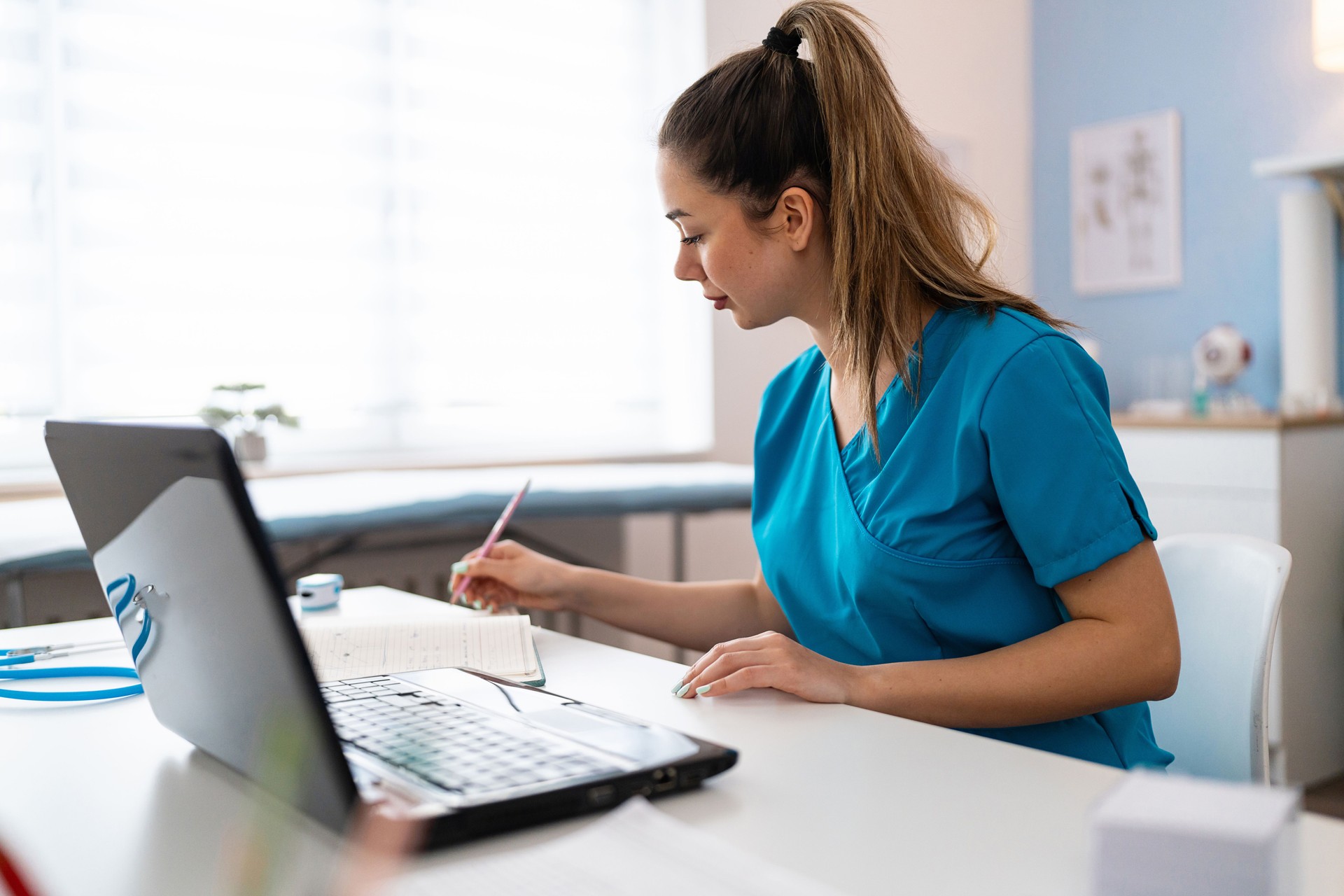 Practicante de medicina con bata médica azul e-learning en computadora portátil en la ordenación